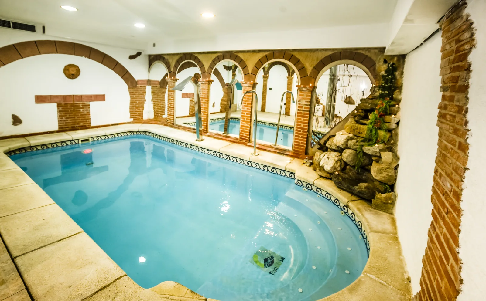 Piscina interior terminada con zona de spa y cascada decorativa